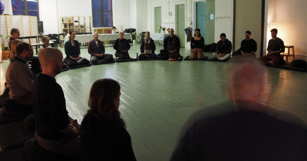 Group of people sitting and meditating in a circle at Zendo